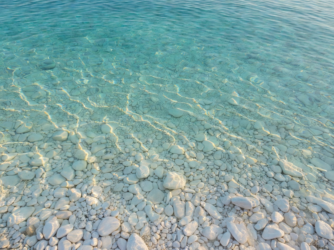 Crystal clear turquoise water over rounded white pebbles in Dalmatia